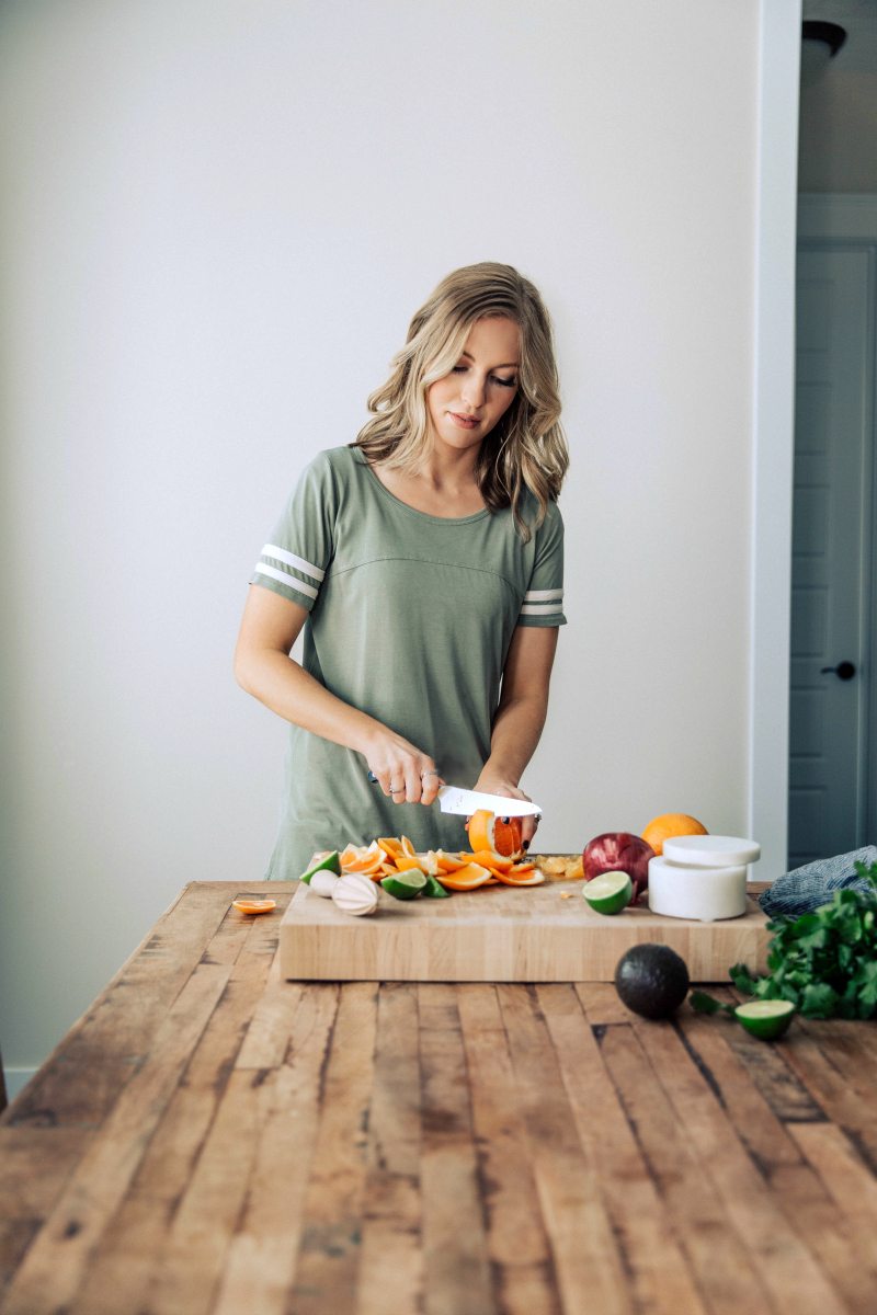 Author preparing citrus avocado salsa to top the healthy and easy grilled mojo chicken