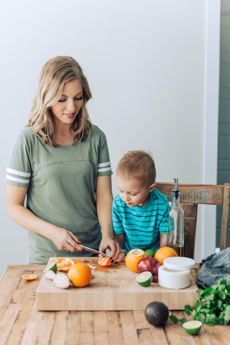 Author cooking with toddler; preparing the citrus avocado salsa to top the mojo chicken