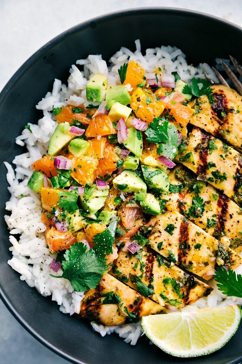 Up close photo of the avocado salsa on top of the grilled cuban mojo chicken on top of the cilantro lime rice