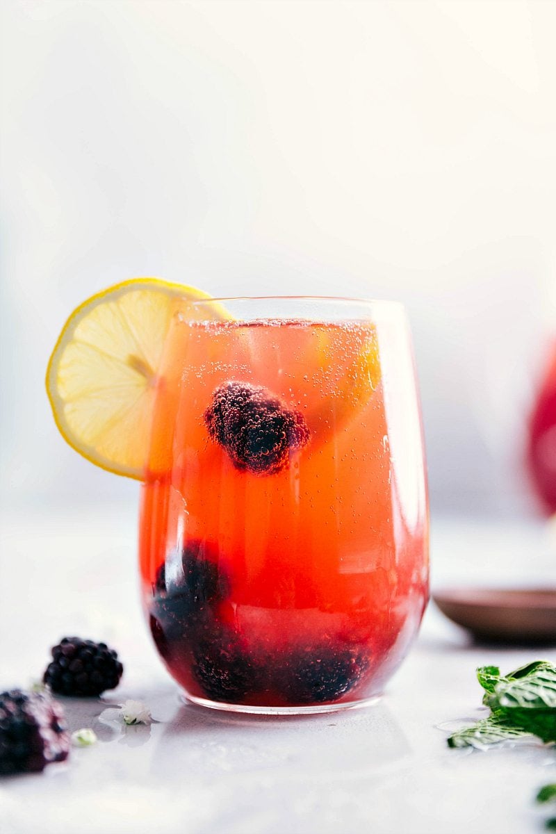 Up-close shot of glass filled with Sparkling Blackberry Lemonade and garnished with a slice of lemon.