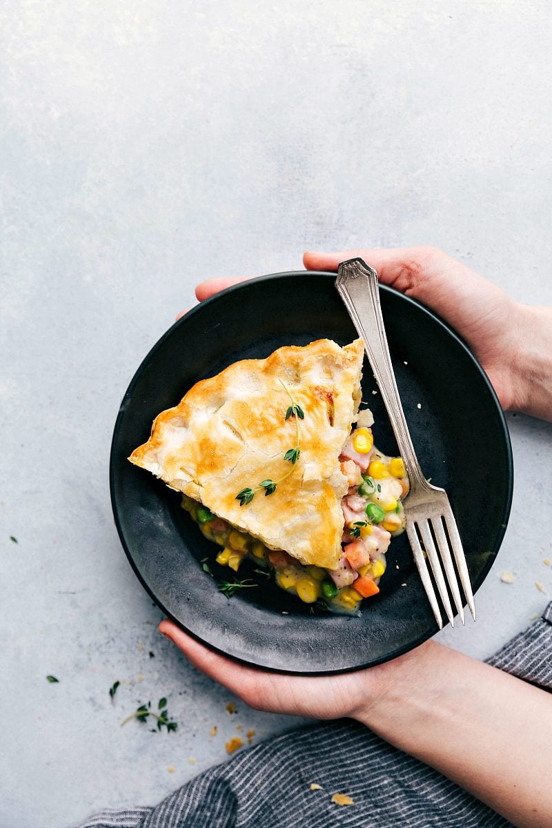 Overhead photo, two hands holding a plate with ham pot pie