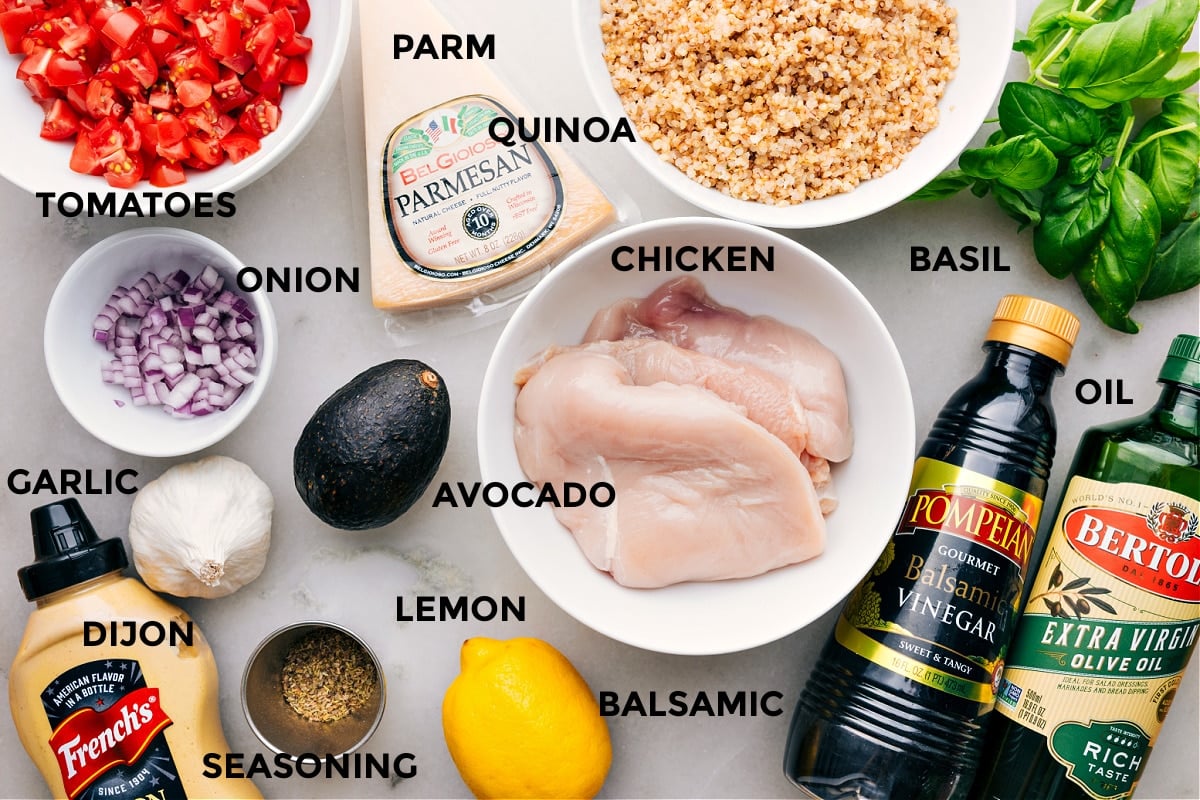 All the ingredients are prepped for easy assembly—tomatoes, Parmesan, quinoa, basil, chicken, avocado, onion, garlic, Dijon, lemon, balsamic, and seasonings.