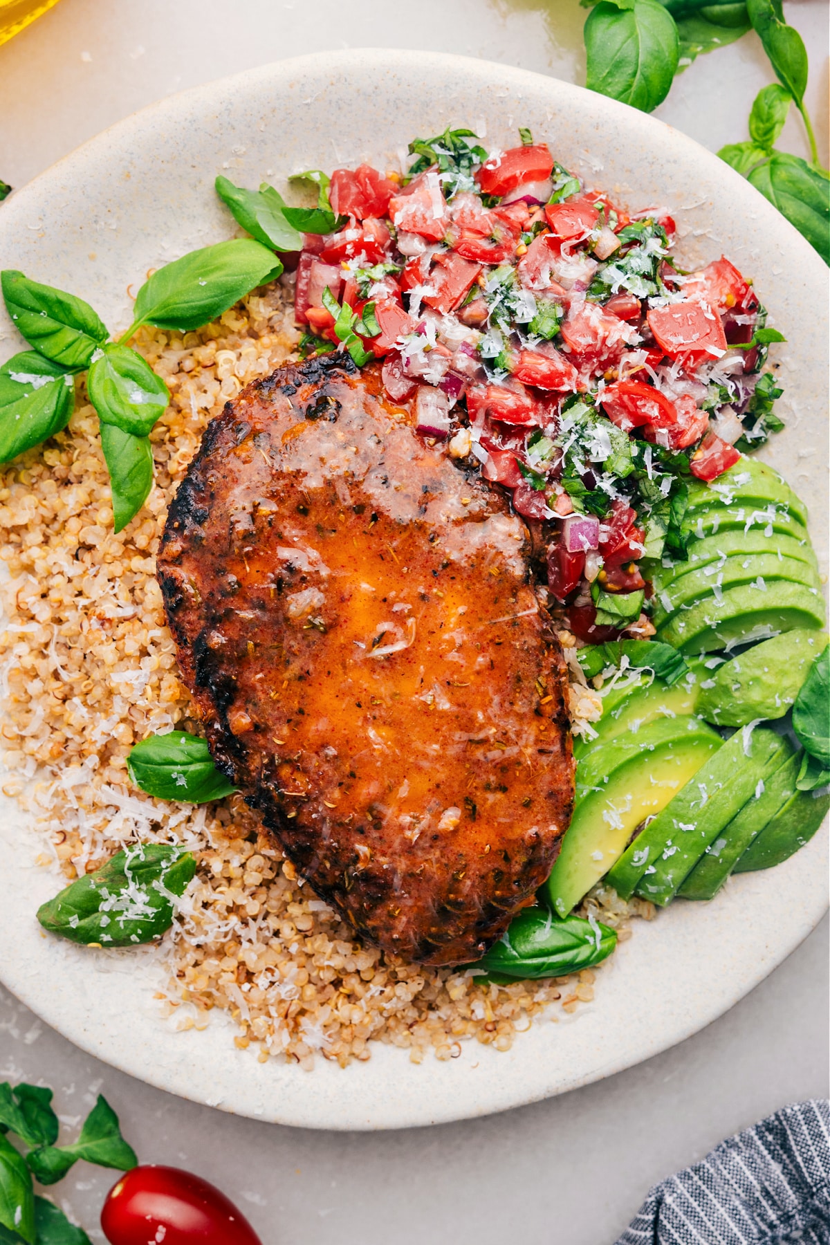 The Ultimate Bruschetta Chicken Recipe Bruschetta Chicken on a bed of quinoa with fresh bruschetta and avocado on the side.