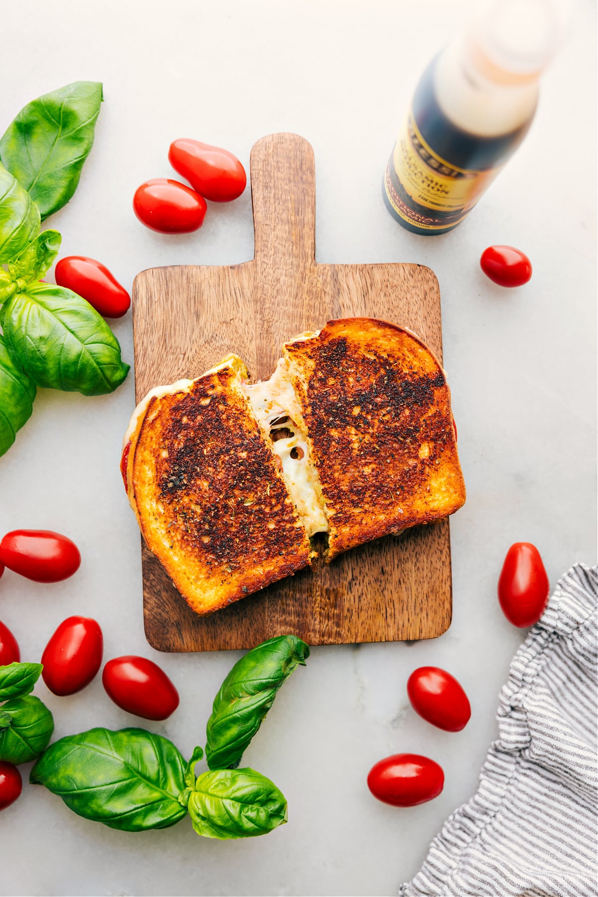 Caprese Grilled Cheese being cut in half with a big cheese pull.