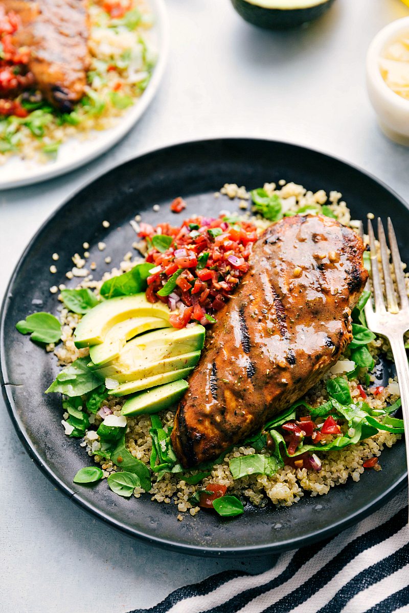 Plate of bruschetta chicken served over quinoa with bruschetta tomato topping and fresh avocado