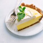 Slice of Lemon Pie on a plate with fresh mint on top.