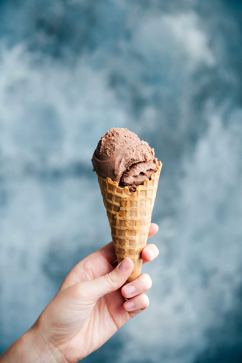 Hand holding a cone filled with chocolate gelato.