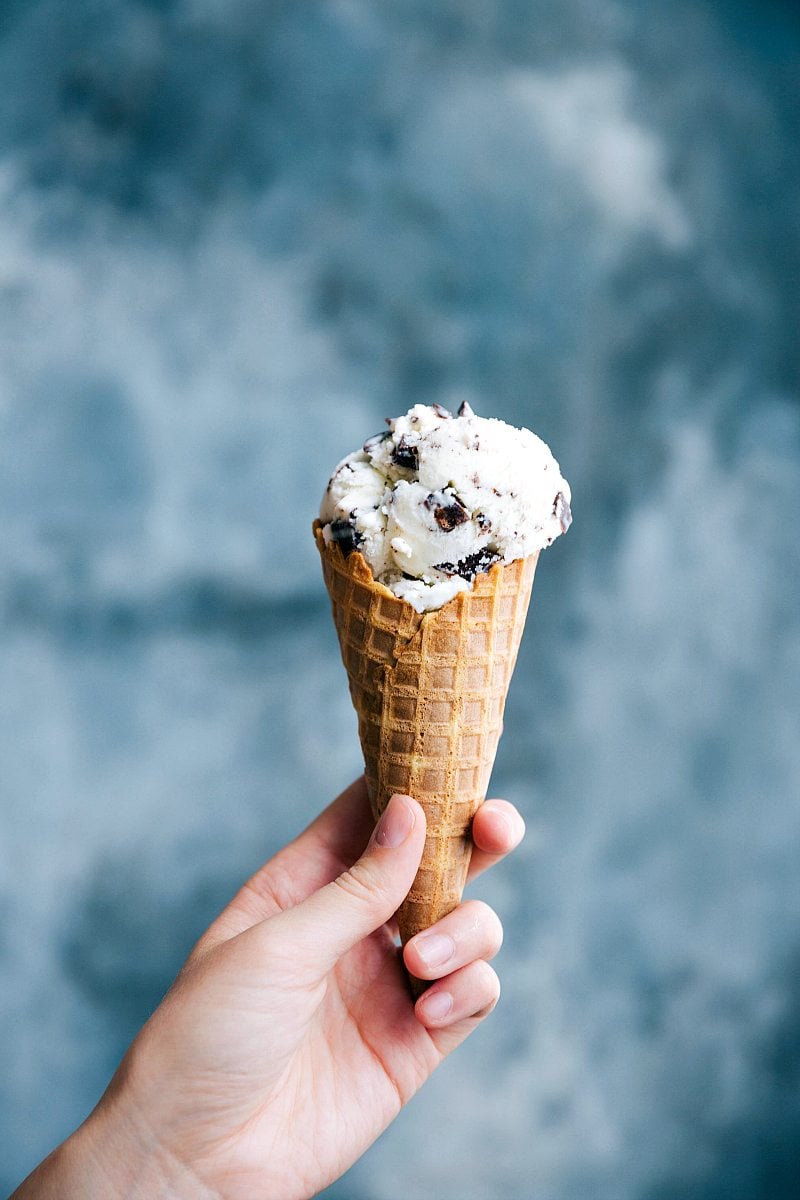 Stracciatella gelato in a waffle cone being held, ready to be enjoyed as a refreshing dessert.