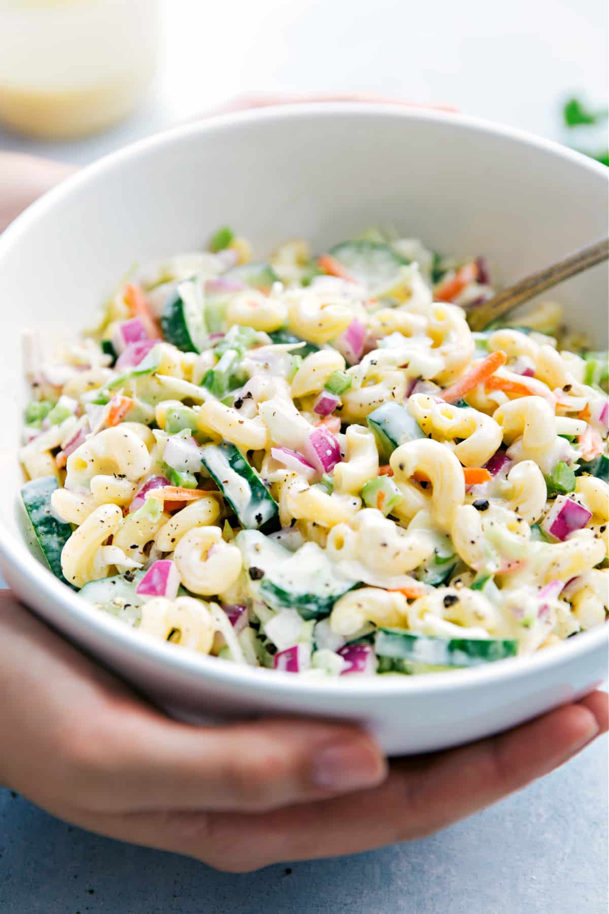 Someone holding a bowl full of the best macaroni coleslaw salad.