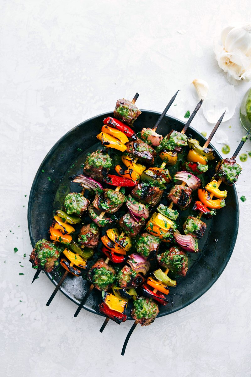 Plate of steak kebabs with basil sauce on top