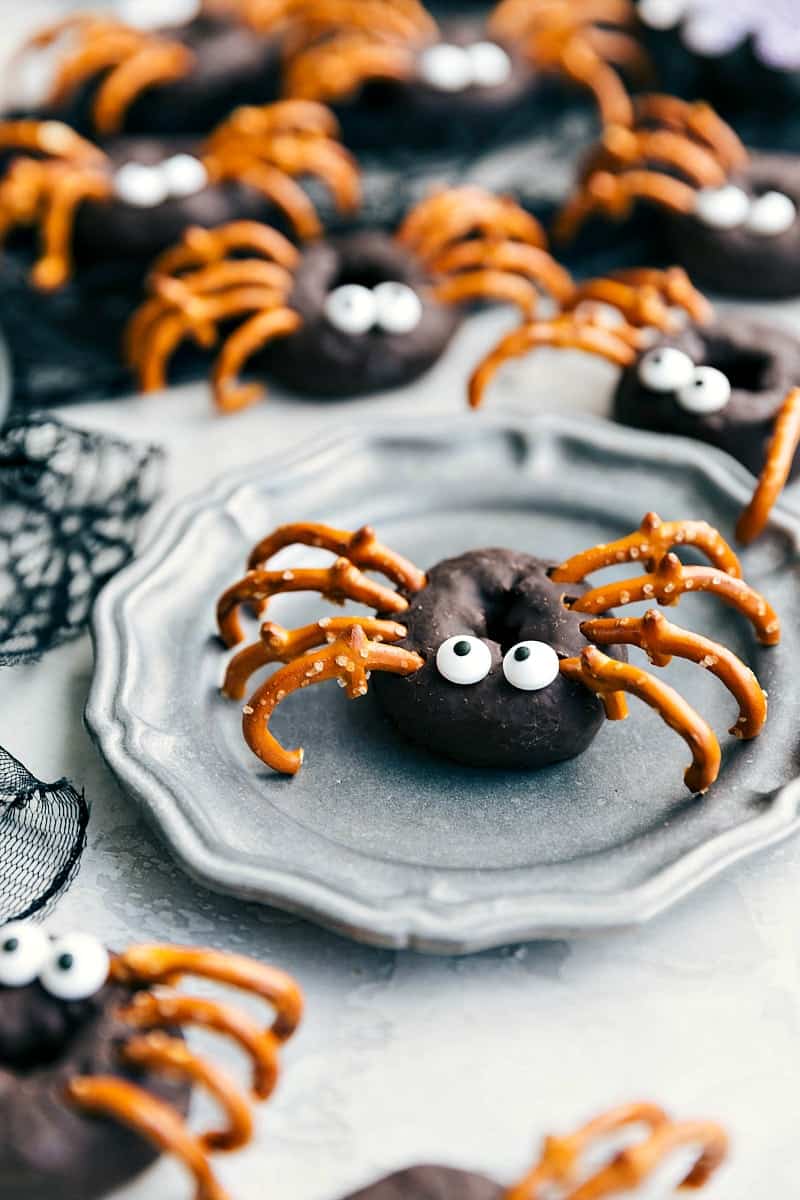 Spider chocolate donuts with candy eyes and pretzels coming out to create spider legs.