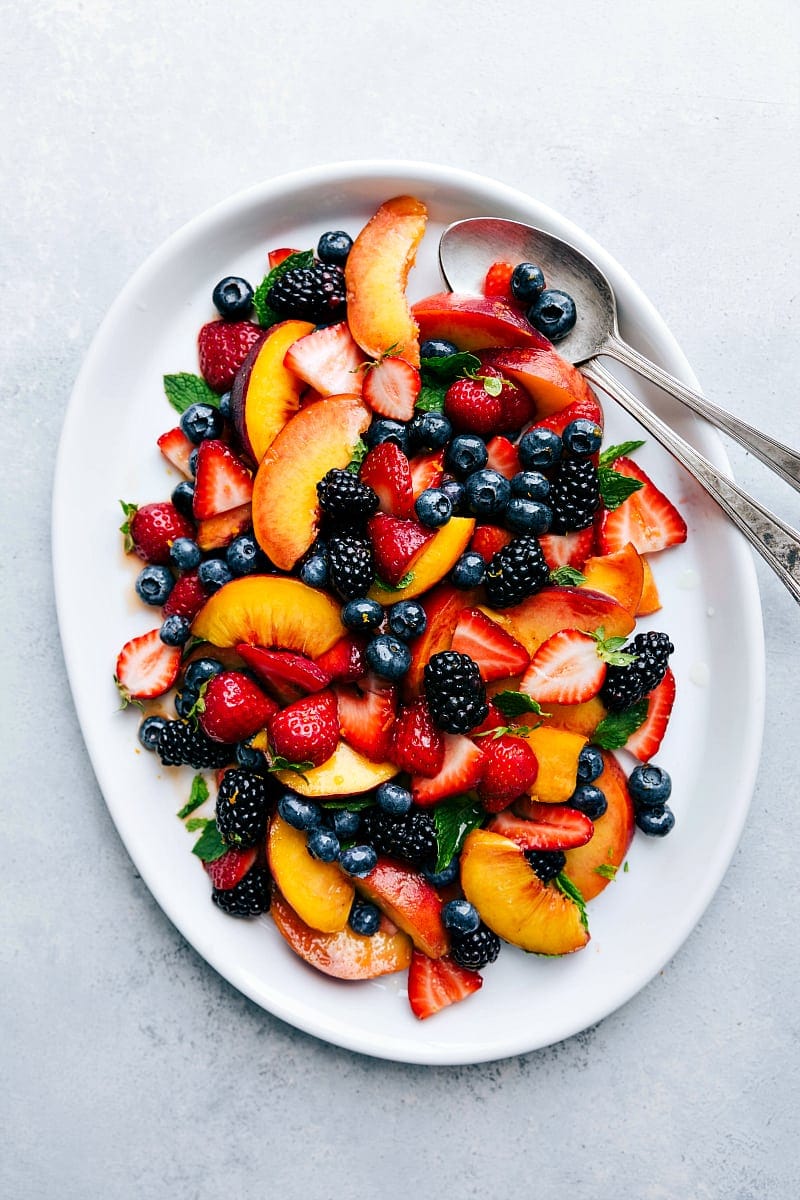 Overhead image of Fruit Salad all on a big platter with two serving spoons.