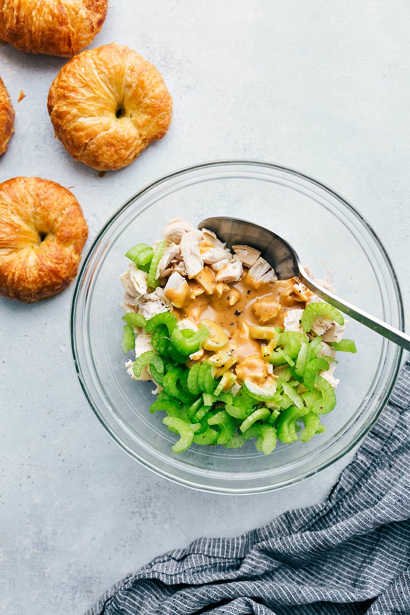 Overhead shot of a bowl of Honey Mustard Chicken Salad sandwich mixture with croissants near the bowl.