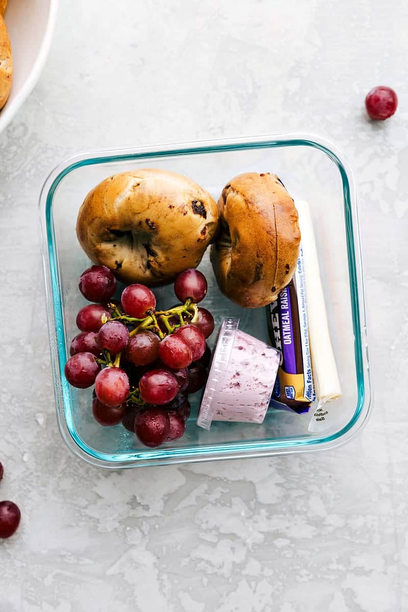 View of a baglel and fruit lunch for school.