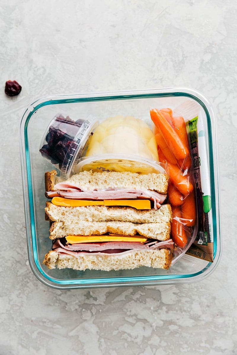 View of a meat and cheese sandwich, fruit, veggies and snack, packed and ready to take to school.