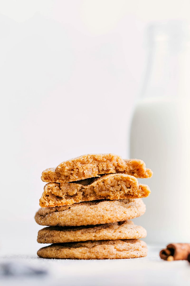 Up-close photo of a stack of Pumpkin Snickerdoodles. The top cookie is broken in half so you can see the soft and chewy interior.