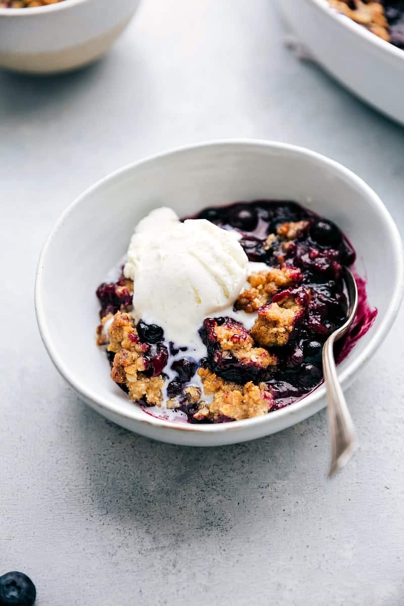The finished, freshly baked dessert in a bowl, featuring a golden crumble topping and juicy filling, topped with a scoop of creamy vanilla ice cream, ready to be enjoyed.