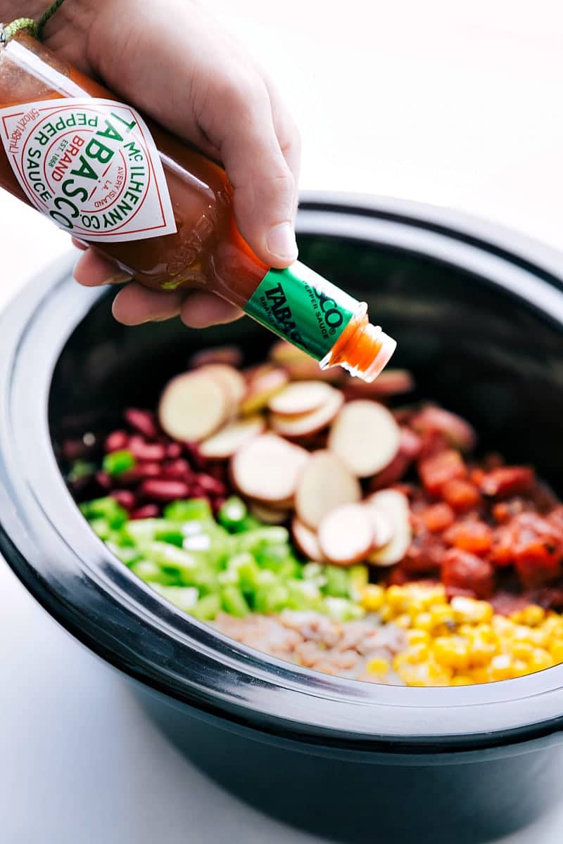 Hot sauce being poured into the crockpot cowboy casserole