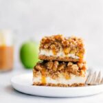 A stack of caramel apple cheesecake bars with mouth-watering layers.