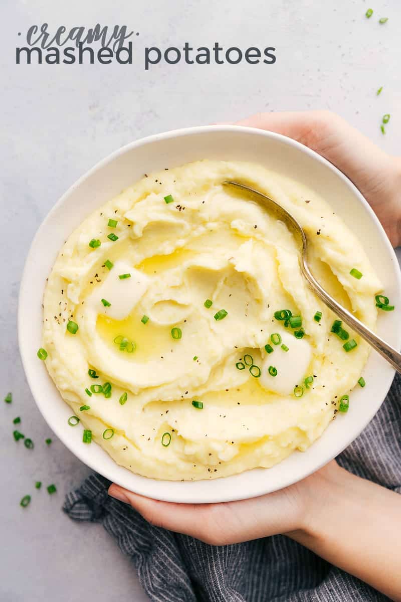 Up close overhead photo of a bowl of mashed potatoes with two hands holding the bowl.