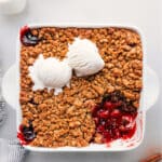 Cherry crisp in a pan with a scoop removed, revealing its delectable contents.