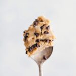 A generous scoop of edible chocolate chip cookie dough sitting temptingly on a spoon, ready to be enjoyed without baking.