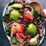 Spinach salad dressed and topped with fresh fruit, ready to be served.