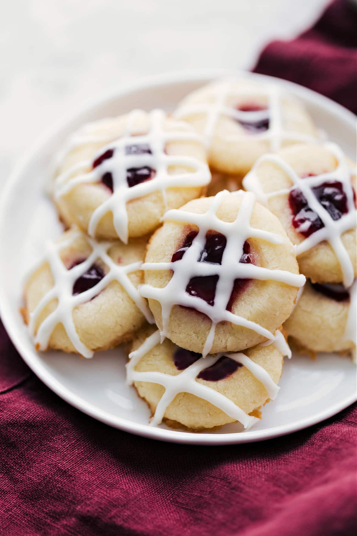 The Best Thumbprint Cookies With Raspberry Filling Thumbprint cookies with a yummy glaze and raspberry filling sit on a plate.