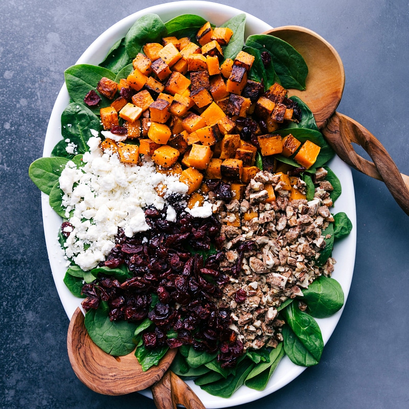 Image of the salad with all the components compartmentalized over a bed of spinach.