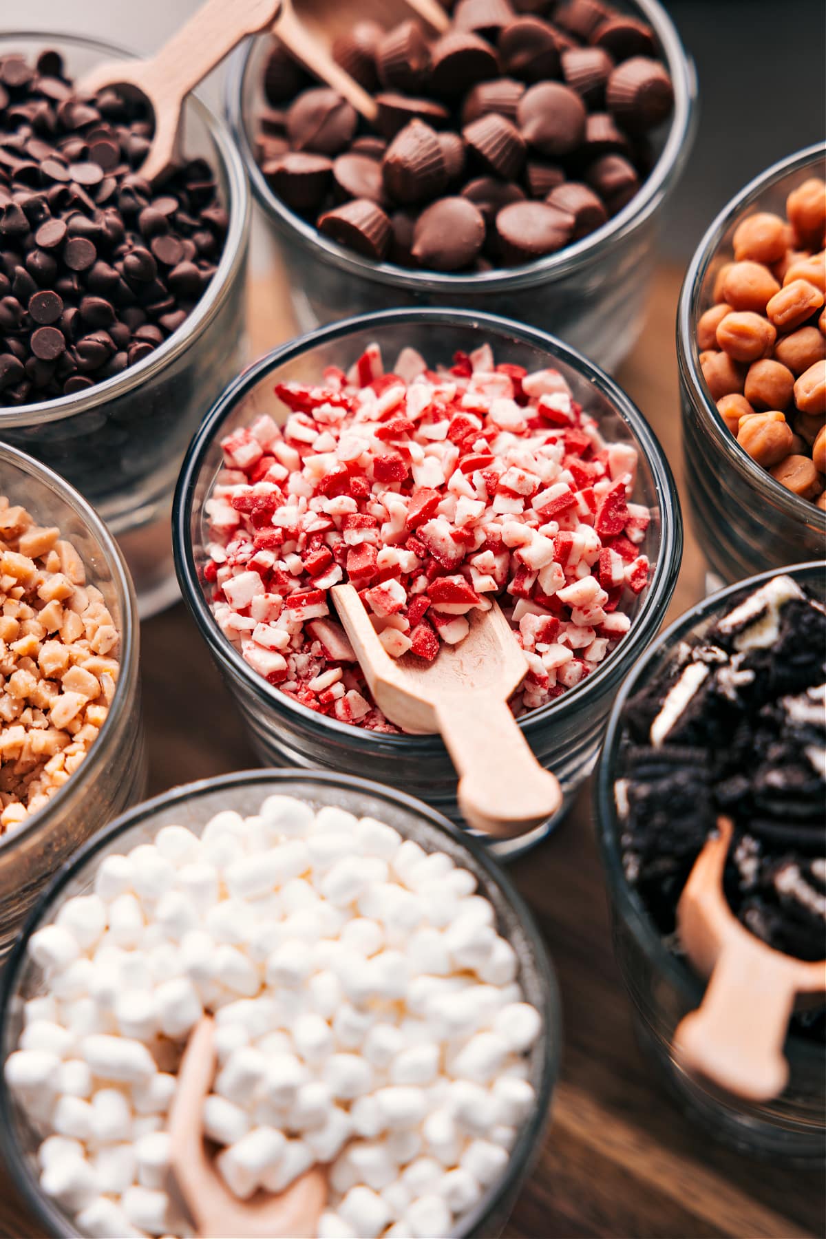 Diverse hot chocolate toppings in glass bowls, each with a scoop nestled inside.