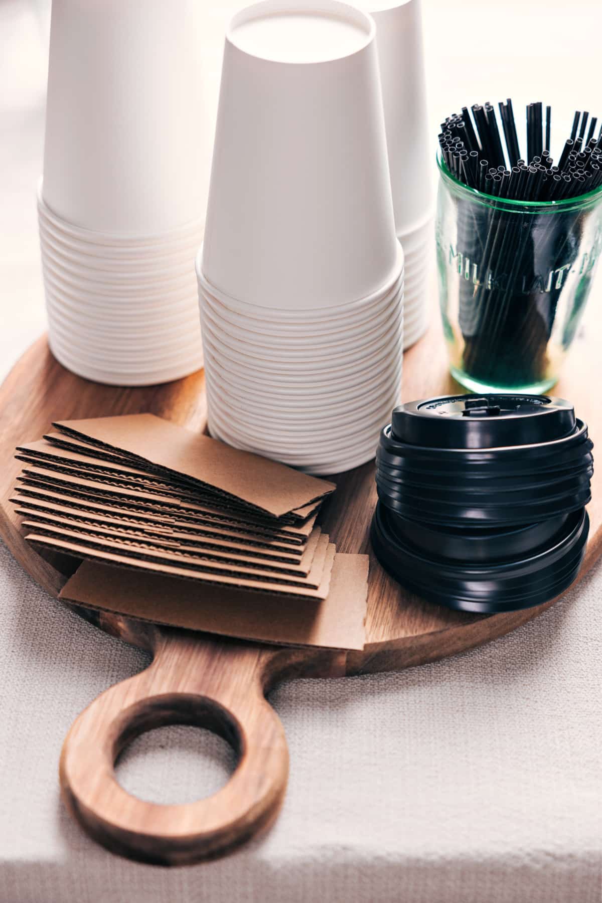Array of hot chocolate cups with lids alongside a selection of straws displayed on a board.