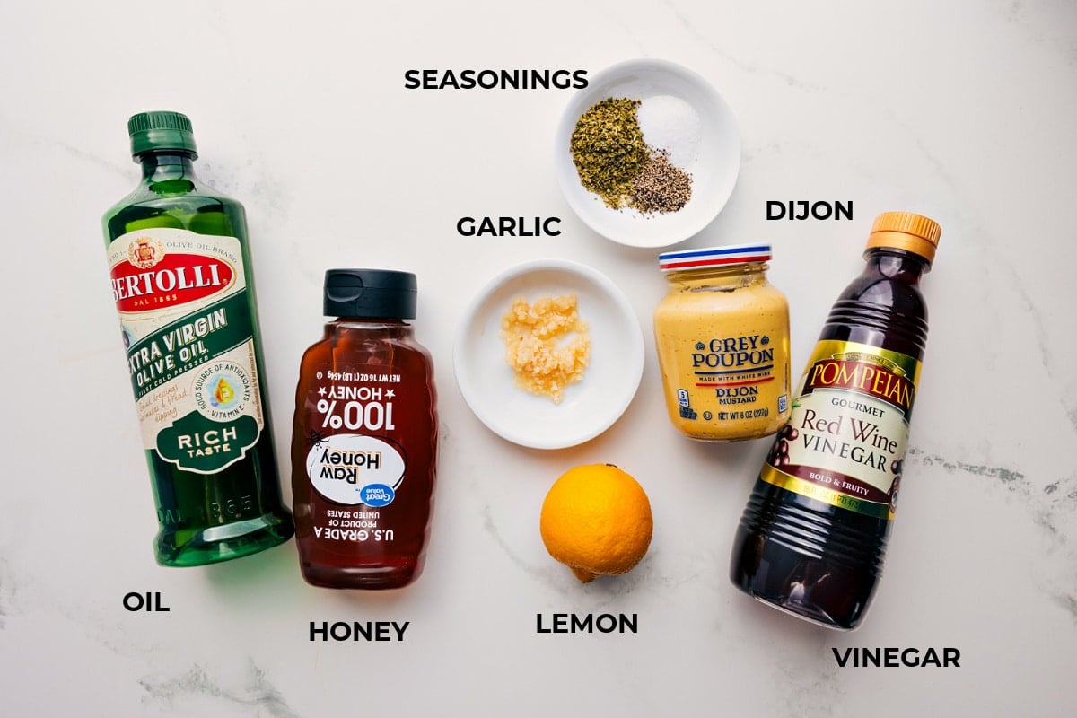 Greek quinoa salad ingredients prepped out for easy assembly including the oil, honey, seasonings, garlic, dijon, vinegar, and lemon.