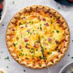 Hearty ham and cheese quiche being sliced to serve.