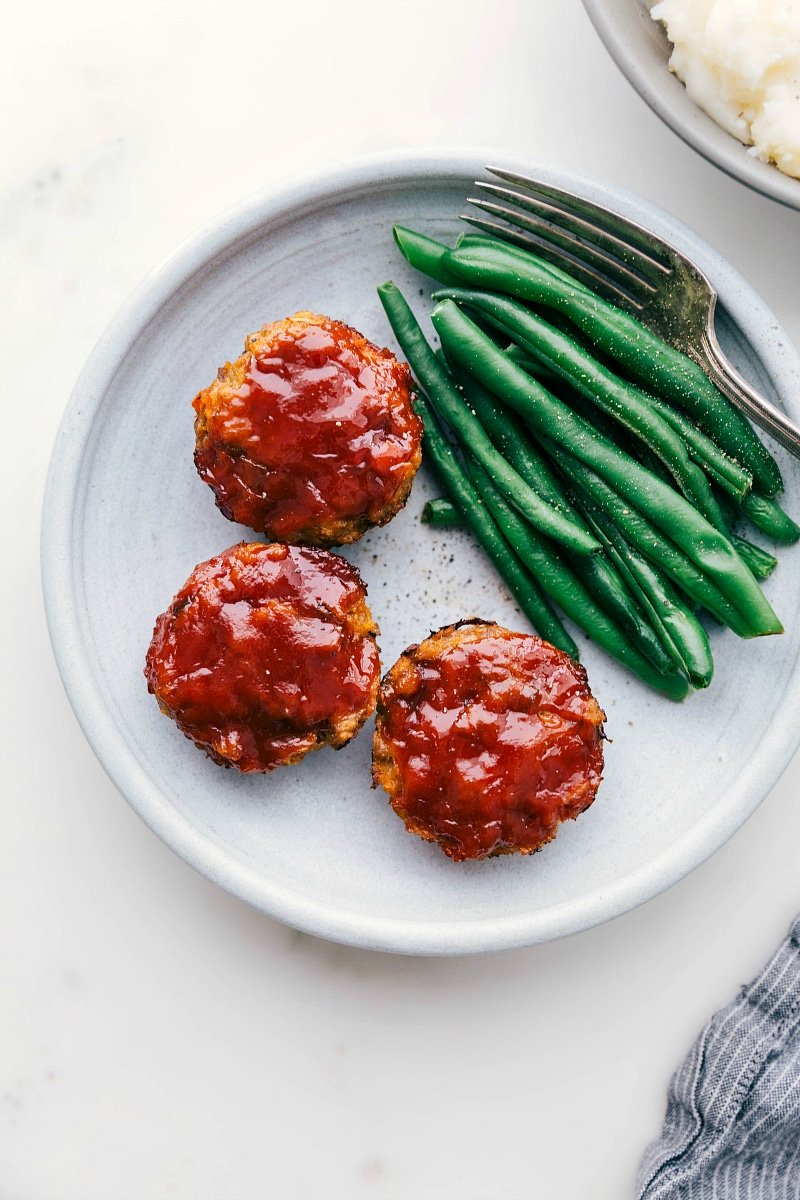 Ready-to-eat mini turkey meatloaves next to green beans.