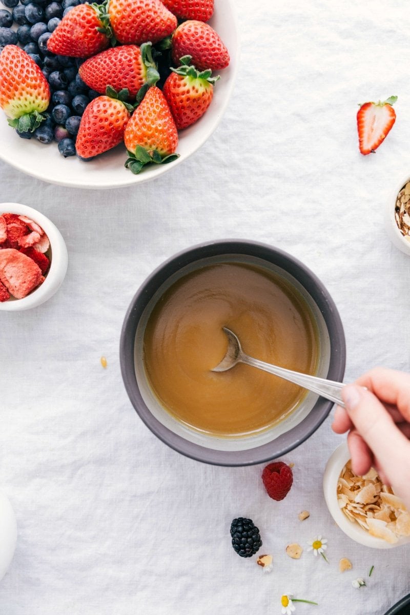 Overhead photo of vanilla sauce in a bowl with berries surrounding it