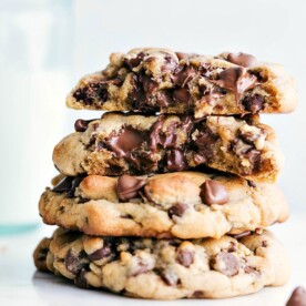 A stack of Bakery-Style Chocolate Chip Cookies with the top two broken in half to see the gooey chocolate center.