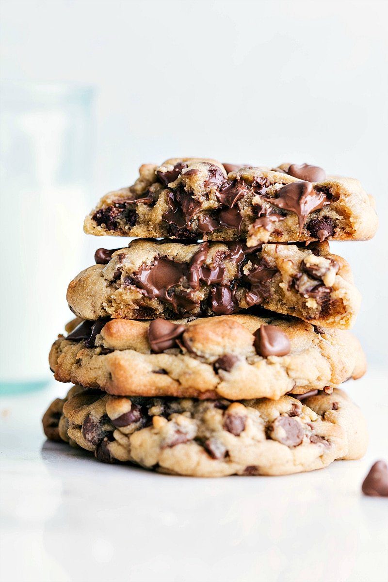 A stack of Bakery-Style Chocolate Chip Cookies with the top two broken in half to see the gooey chocolate center.