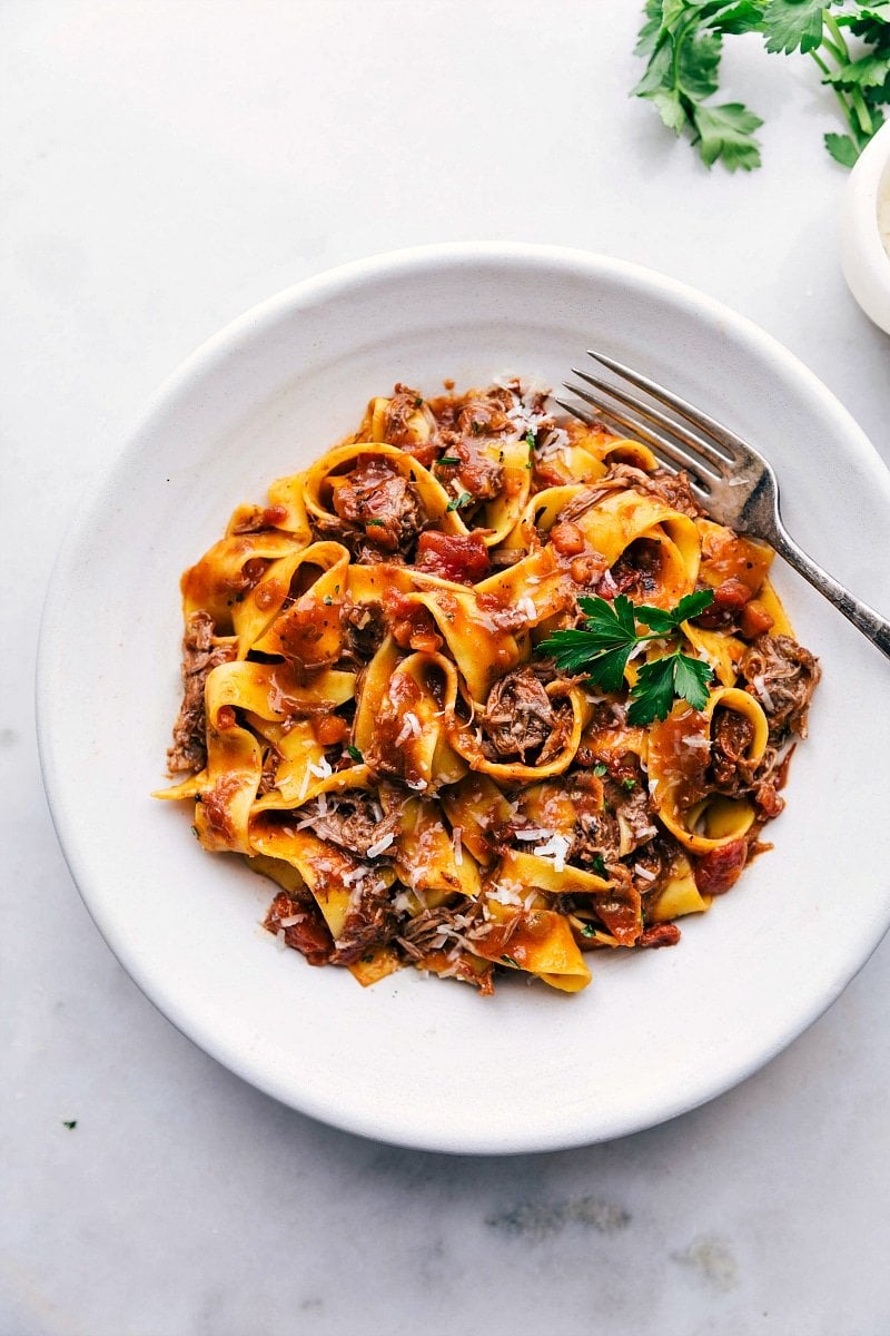 Overhead photo of a bowl of Beef Ragu with fresh parsley and Parmesan cheese.