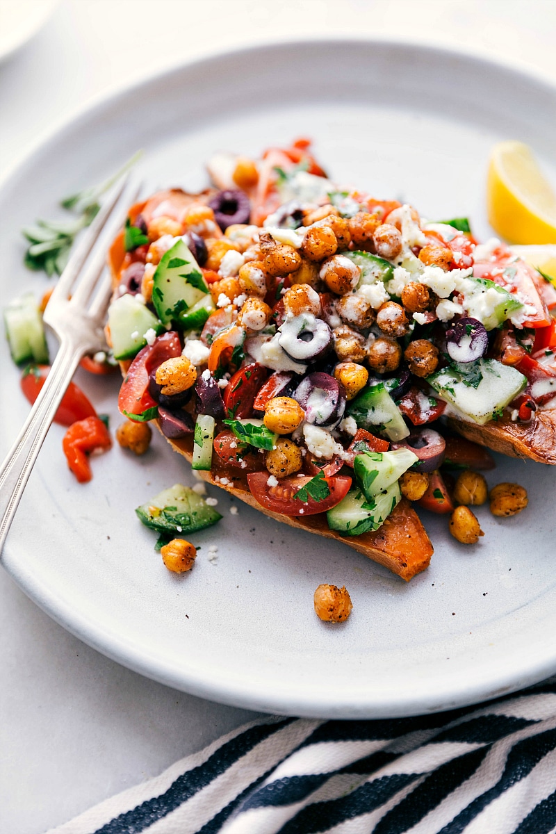 Overhead image of the Mediterranean Sweet Potatoes on a plate with the topping on top and dressing drizzled over them.