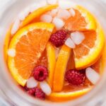 Drink with the oranges, raspberries, and ice on top.