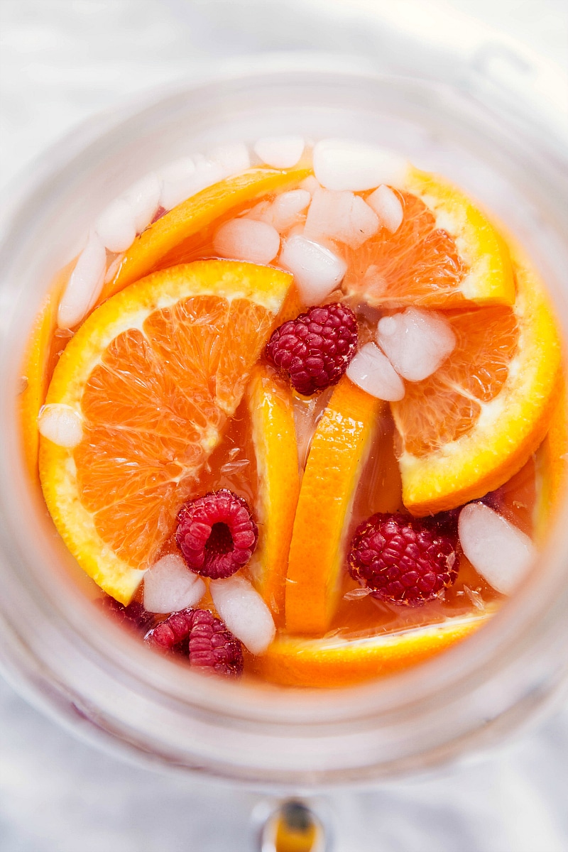 Drink with the oranges, raspberries, and ice on top, ready to be enjoyed.