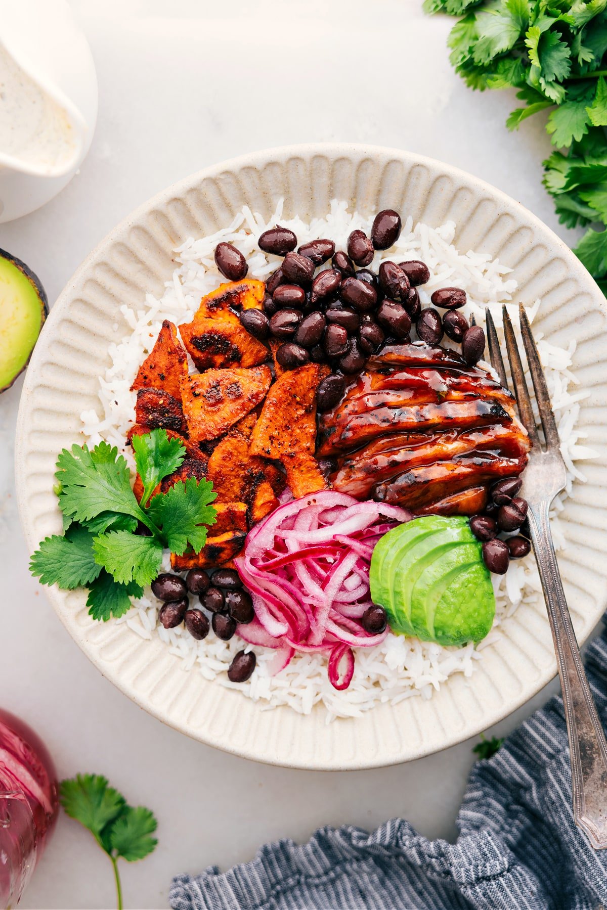 The best BBQ Chicken Bowl Recipe BBQ Chicken Bowl with rice, sweet potatoes, onions, avocado, and beans.