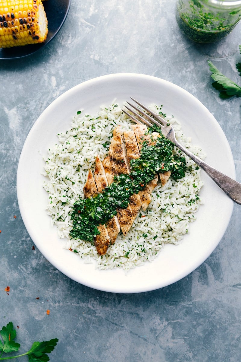 One of our favorite healthy and easy dinner recipes is Chimichurri Chicken! An addictive green herb sauce drizzled over simple spice-rubbed boneless chicken breasts (or thighs) makes for a flavor-packed meal. chelseasmessyapron.com #argentina #uruguay #grilled #chimichurri #chicken #marinated #easy Overhead shot of Chimichurri Chicken on a bed of rice.