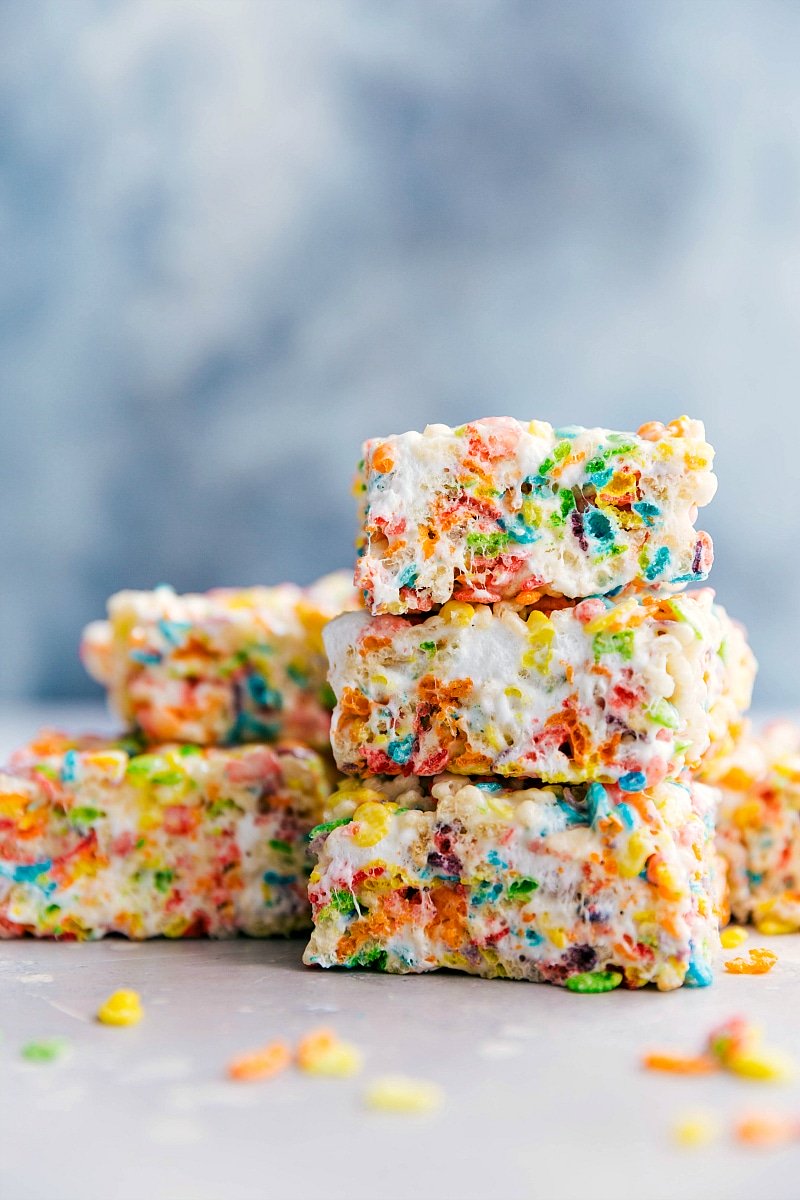 Fruity Pebbles Rice Krispies Treats stacked on a board.