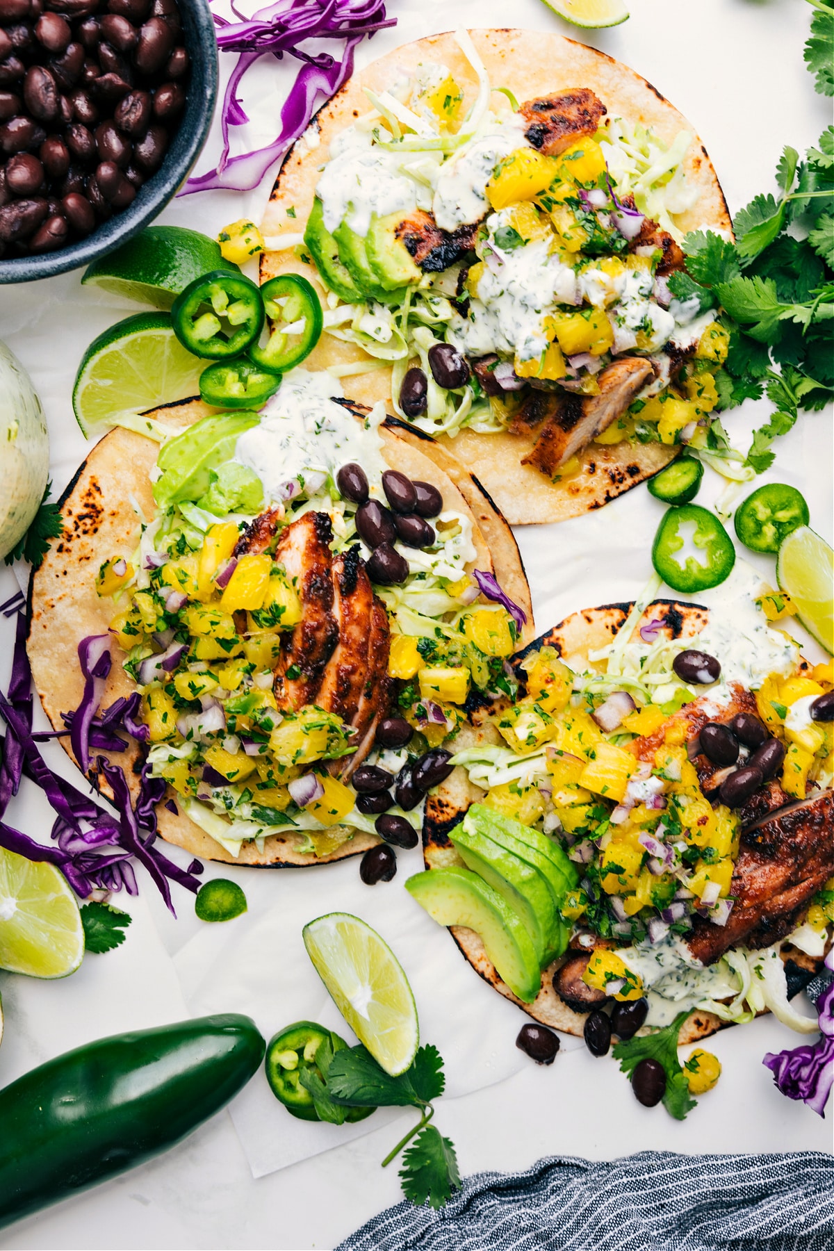 Jamaican jerk tacos made with spice-rubbed chicken, a mango black bean salsa, and a delicious jalapeño-cilantro sauce. #jamaican #jerk #tacos #mango #salsa #black #bean #avocado #lime