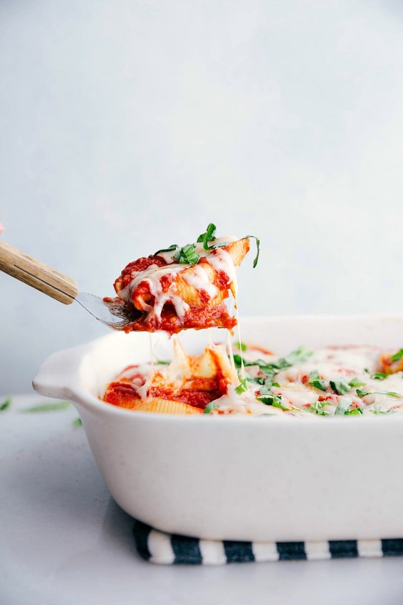 Spatula pulling up a stuffed shell from the pan.