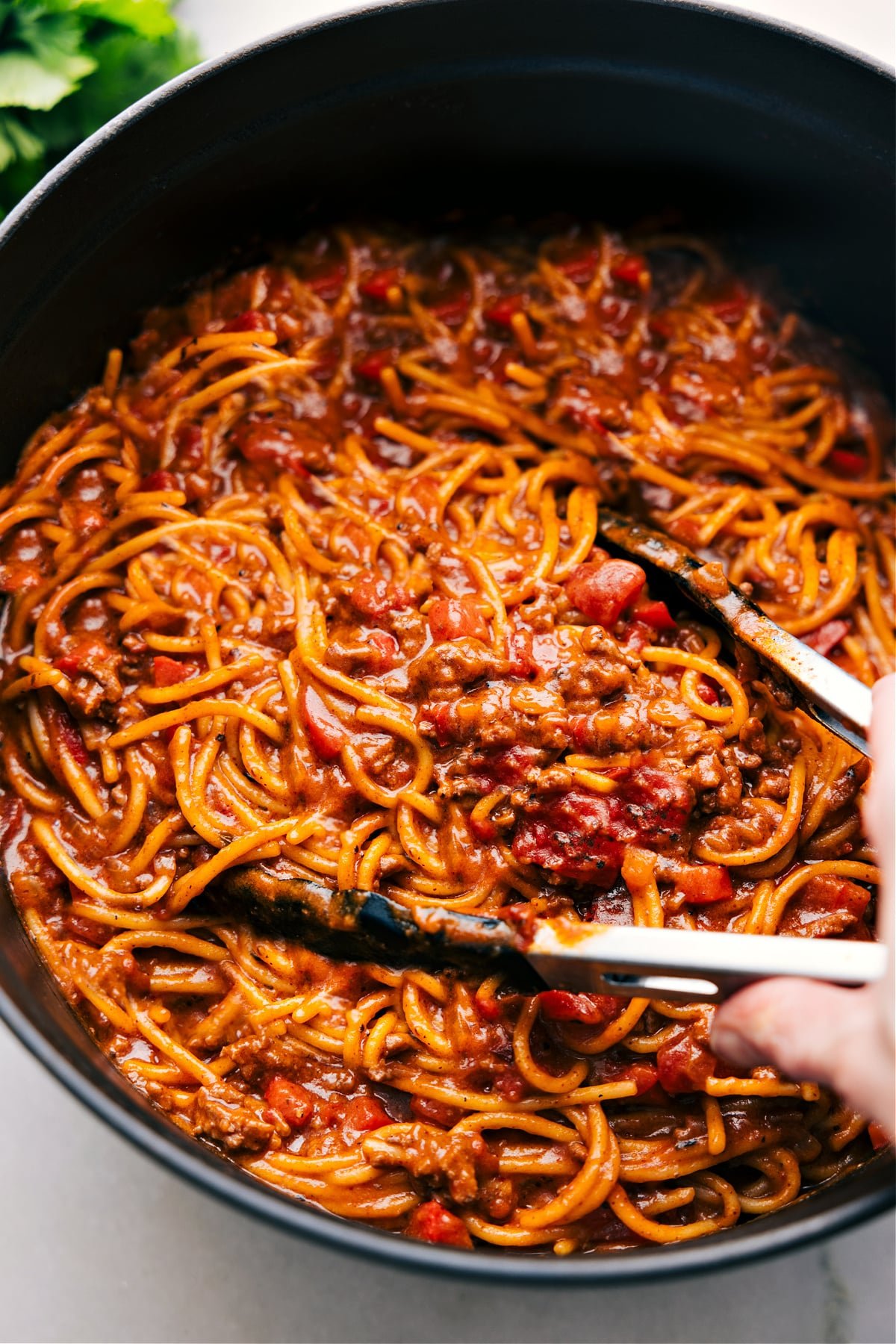 Taco Spaghetti in a pot with tongs about to scoop some up.