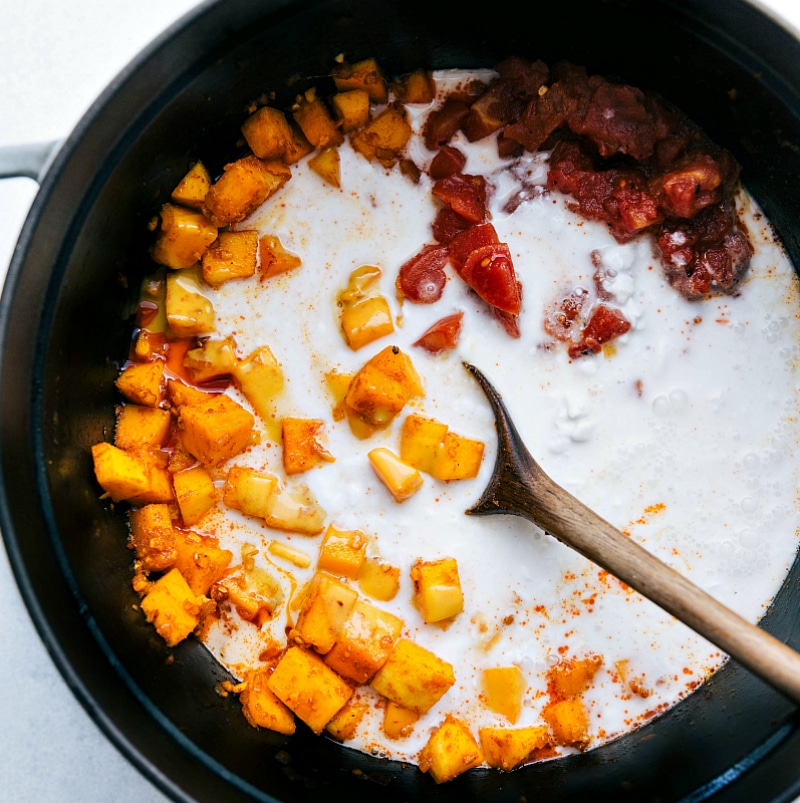 Coconut milk being added to the pot with the other ingredients.