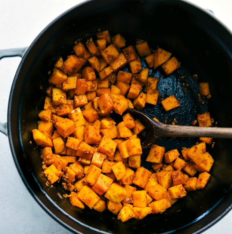 Butternut squash cubes being cooked with spices.