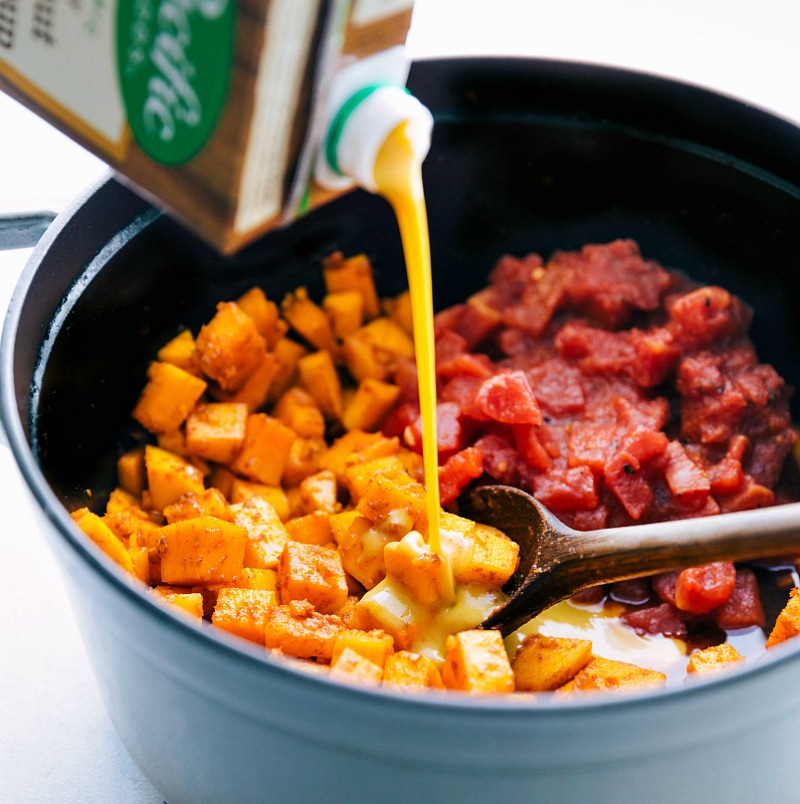 Image of the soup being added to the other ingredients in the pot for this Butternut Squash Curry.